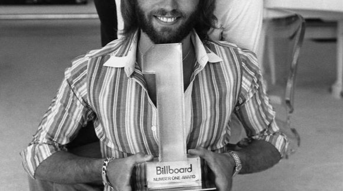 Maurice Gibb of the Bee Gees holding a Billboard Number One Award in 1977, the year before stayin alive topped the charts