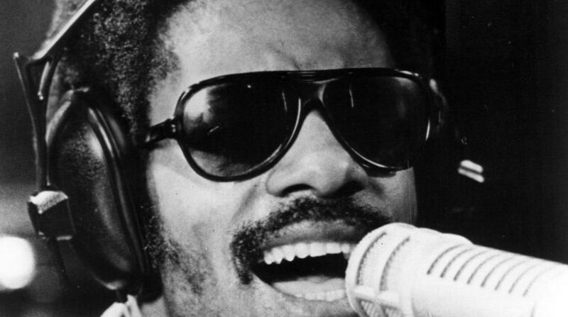 Stevie Wonder singing into a studio microphone in 1973, the year he placed three singles on the year-end Hot 100